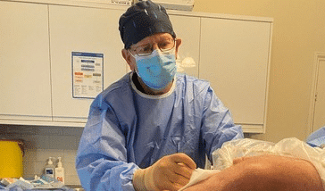 Healthcare professional in surgical attire performing medical procedure