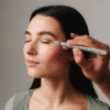 Eyelid Blepharoplasty makeup artist applying eyeshadow to woman's eyelid with brush