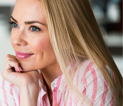 Woman with long blonde hair wearing pink striped shirt