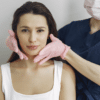 Liquid facelift vs surgical facelift Healthcare professional examining patient's face with gloved hands